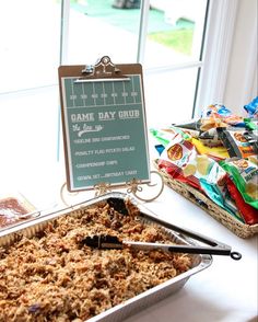 a table topped with a pan of food next to a sign that says game day club