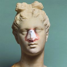 a white statue with a piece of paper stuck to it's face and nose