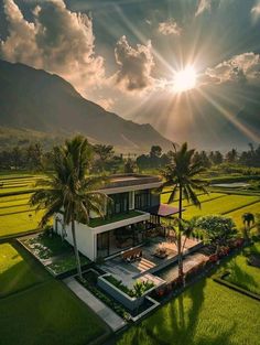 an aerial view of a house in the middle of rice fields with mountains in the background