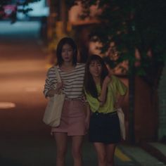 two young women walking down the street at night