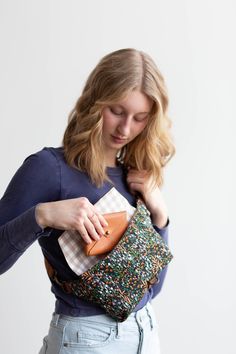 a woman holding a purse in her right hand and looking down at the other side