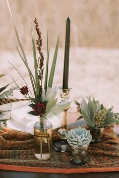 an arrangement of succulents and candles on a table