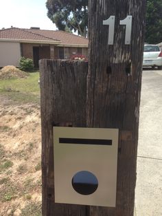 a close up of a wooden pole with a sign on it's side and a house in the background