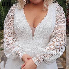 a woman wearing a white wedding dress with long sleeves and lace detailing on her arms