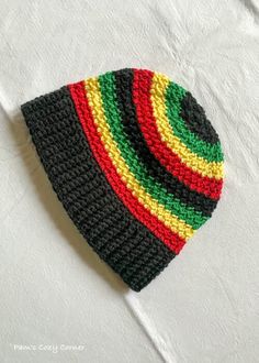 a multicolored knitted hat laying on top of a white sheet