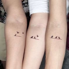 two people with matching tattoos on their arms are sitting next to each other and one has a small bird tattoo on the arm