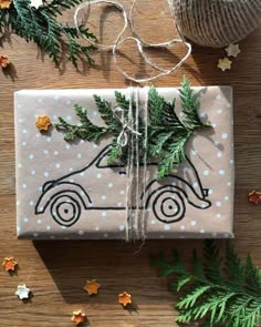 a wrapped present sitting on top of a wooden table next to christmas decorations and greenery