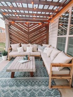 an outdoor living area with couches, tables and lights