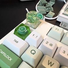 a computer keyboard with green and white keys sitting on a desk next to other electronic devices