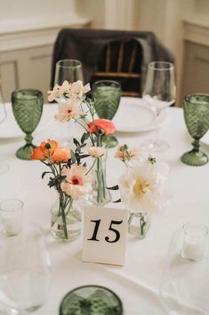 the table is set with flowers in vases and place cards for guests to sit at