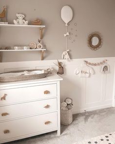 a baby's room with a crib, dresser and teddy bear decorations on the wall