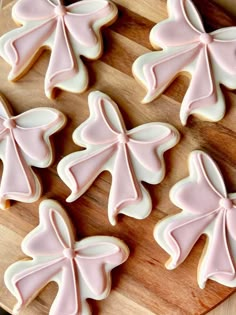 decorated cookies on a cutting board with pink icing in the shape of bows and leaves