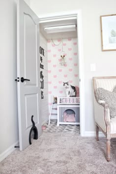 a cat sitting on top of a bed in a closet next to a chair and wallpaper