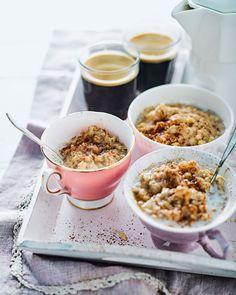 three bowls filled with oatmeal sitting on top of a tray next to cups