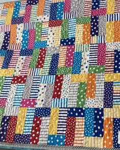 a multicolored quilt with polka dots and stripes on the bottom, in different colors