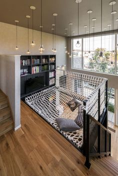 a living room filled with lots of furniture next to a book shelf and stairs in front of a window