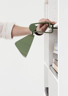 a person holding a green lamp in front of a book shelf with books on it