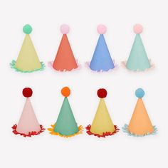 six party hats with pom poms on each one, all in different colors