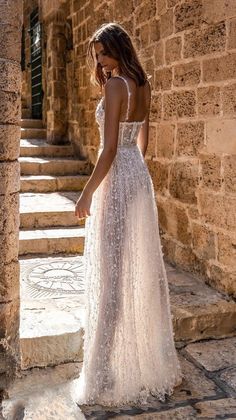 a woman in a white dress is standing on some steps and looking down at the ground