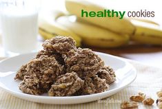 a white plate topped with cookies next to bananas and a glass of milk on a table