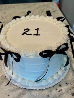 a white cake with black ribbons and the number 21 on it's bottom layer