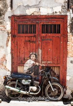 a motorcycle parked in front of a red door with a painting on it's side