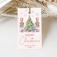 a christmas card hanging from a tree on a white background with snowflakes around it