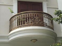 a balcony with an iron railing and wooden door on the side of a white building