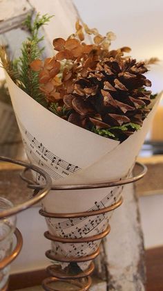 a bunch of pine cones sitting on top of a metal stand with music notes and evergreen branches