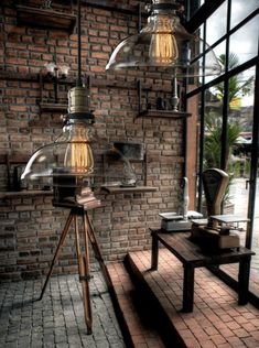 an industrial style lamp hanging from the side of a brick wall next to a wooden table