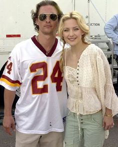 a man and woman standing next to each other in front of a white truck with the number 24 on it