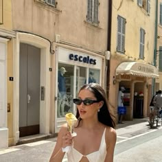 a woman is walking down the street eating an ice cream