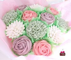 cupcakes decorated with pink, green and white frosting are in a bouquet