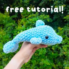 a hand holding a blue stuffed animal with the words free pattern on it and trees in the background