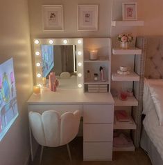 a white vanity with lights on it next to a bed and a desk in front of a mirror