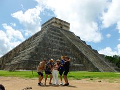 four people standing in front of an ancient pyramid