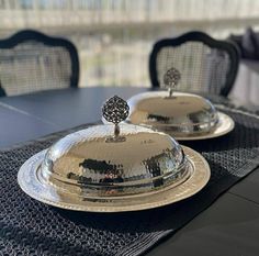 two silver dishes sitting on top of a table