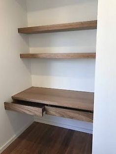 an empty room with some shelves on the wall and wood flooring in front of it