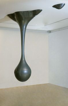 a large black vase hanging from the ceiling in an empty room with no people around it