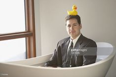 a man sitting in a bathtub with a rubber ducky on top of his head