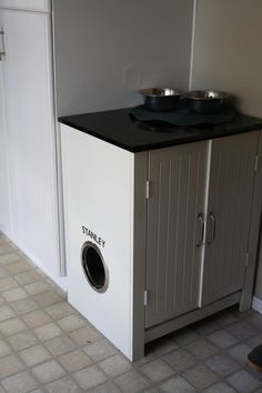 a dog bowl is on top of a cabinet in the middle of a tiled floor