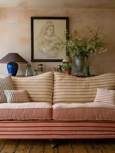 a living room with a striped couch and two vases on the table next to it