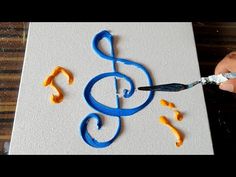 someone is painting music notes on paper with blue and yellow paint while holding a pair of scissors