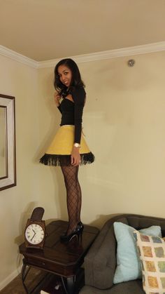 a woman standing on top of a bed wearing tights and heels with a clock in the background