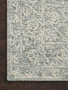 an area rug that is on top of a wooden floor with a white and blue pattern