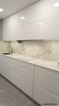 a kitchen with white cabinets and marble counter tops on each side, along with a sink