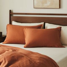 a bed with two pillows and an orange blanket