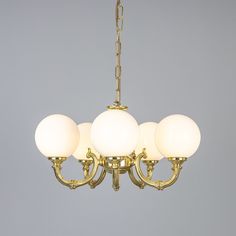 a chandelier with five white glass balls hanging from it's center chain