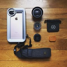 an iphone, camera and other accessories laid out on a wooden floor