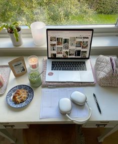 an open laptop computer sitting on top of a desk next to a plate of food